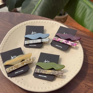 Détail de barrettes à perles en divers coloris dont gris bleu et rouge bordeaux