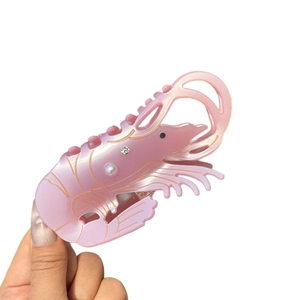 Pink shrimp hair claw clip with pearl and rhinestone details in pearlescent acetate