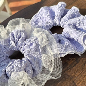 Detailed view of lavender purple scrunchie with white lace edges and soft fabric texture