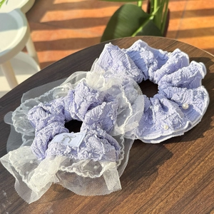Detail of lavender lace scrunchies with white pearls and bow label on a wooden surface