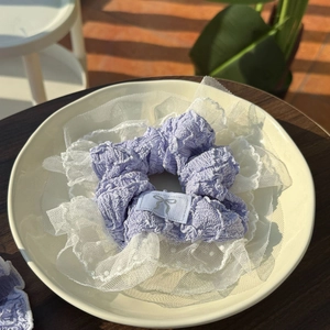 Detailed shot of lavender lace scrunchie with white polka dot mesh and silver bow label