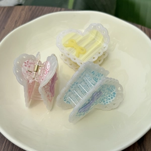 Dettaglio di pinze per capelli a cuore rosa, giallo e blu con bordi in pizzo e fiocco