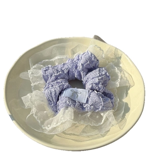 Lavender purple scrunchie with lace trim and bow patch shown on a ceramic plate