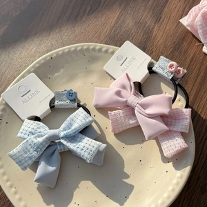 Detailaufnahme von hellblauen und rosa Satin-Haarschleifen-Sets auf einem Holztisch