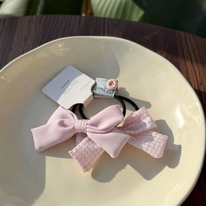 Nahaufnahme von rosa Schleifen-Haargummis mit Spitze und Knöpfen auf Keramikteller