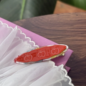 Detailansicht der Haarspange aus Essigsäure mit rotem Apfeldesign und Marmortextur