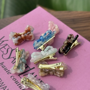 Detail of mini acetate bow hair clips in multiple colors with gold metal bases