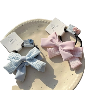 Rosa und blaue doppellagige Haargummis mit Karomuster und Knopfdetails auf Karte