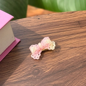 Close-up of pink and beige acetate bow hair clip with vintage marble texture on wood