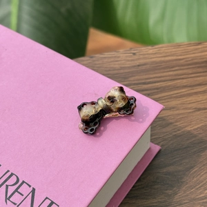 Macro detail of tortoiseshell acetate bow clip with gold metal base on book