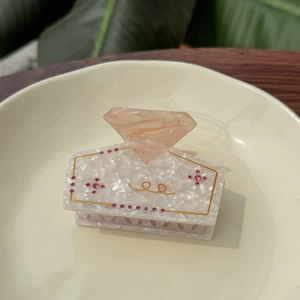 Elegant marble acetate square hair claw with crystals and gold accents on ceramic tray