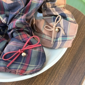 Detail of plaid fabric hair ties with faux suede bows and golden beads on ceramic plate