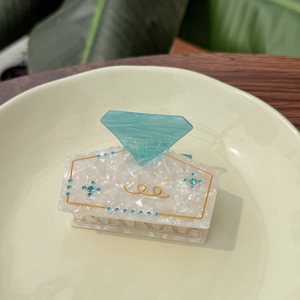 Elegant acetate shark hair claw clip with blue diamond accent and white pearl finish