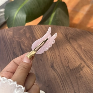 Detail der rosa Flügel Haarspange aus Harz mit Kristallen auf goldenem Entenschnabelclip