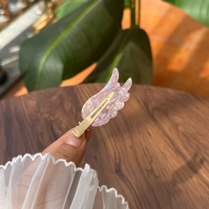 Detail der rosa Acetat-Flügel-Haarklammer mit Strasssteinen und goldenem Metallsockel