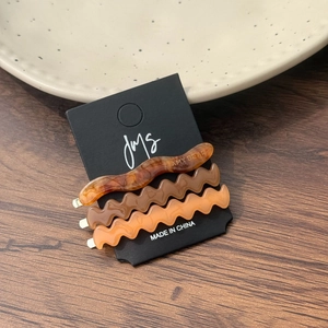 Lot de trois barrettes à cheveux ondulées en acétate aux tons ambrés sur bois