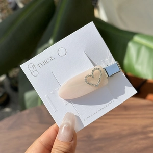 Elegante beige hars haarklem met sprankelend strass hart op een displaykaartje
