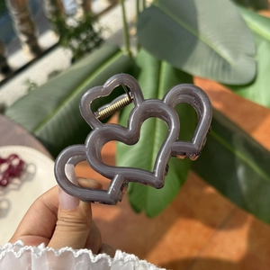 Pinza de pelo con diseño de corazón gris oscuro efecto gelatina bajo luz natural