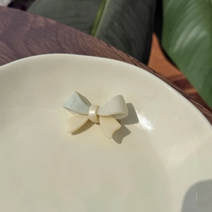 Elegant acetate bow hair clip with pearl luster in soft green and cream marble finish
