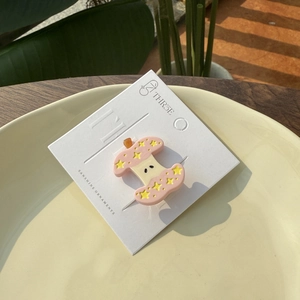 Pince à cheveux rose en forme de pomme avec étoile jaune sur carte blanche