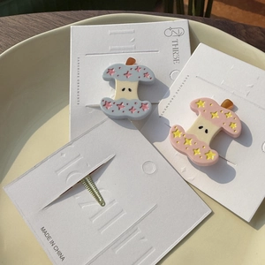 Gros plan de barrettes pomme à motifs étoiles avec des finitions en acétate rose et bleu