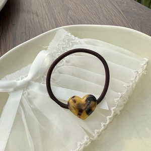 Detail of heart-shaped leopard print hair tie with France handmade gold logo