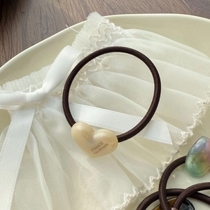 Close-up of brown elastic hair tie with cream heart charm and France Handmade text