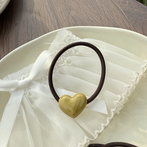 Detail of amber resin heart pendant with marble texture on dark brown hair tie
