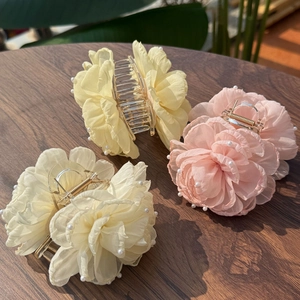Detailed view of chiffon flower hair clips with pearl edges and gold metal claws
