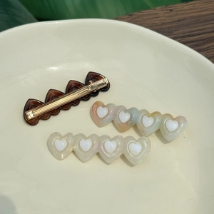 Three acetate heart hair clips in tortoiseshell and marble patterns on a white plate