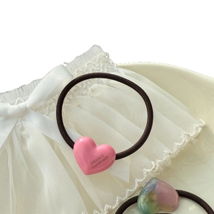 Handmade heart-shaped elastic hair ties with gold lettering on soft lace background