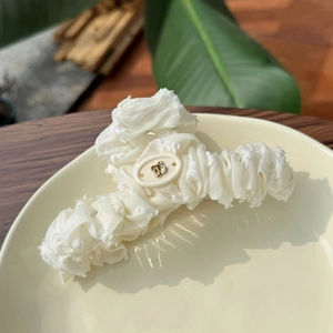 Pince à cheveux élégante en tissu plissé blanc avec détail d'insecte doré sur assiette