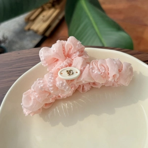 Pince à cheveux rose en mousseline froissée avec bouton blanc et abeille dorée sur plat