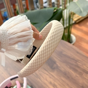 Detail of cream waffle texture headband with a handmade label and soft woven fabric