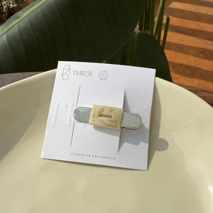 Minimalist acetate hair clip with cream marble texture and silver base on display