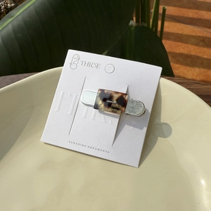 Minimalist tortoiseshell acetate hair clip with hollow waist design on display card
