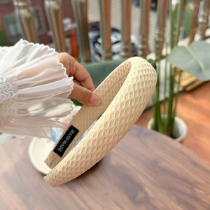 Detail of beige padded headband with waffle texture and interior handmade woven label