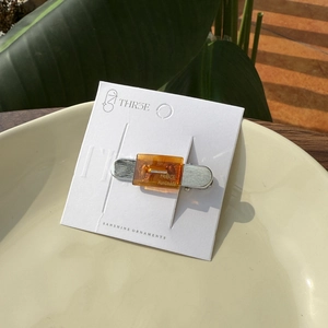 Hollow acetic acid hair clip with amber resin finish on silver metal base