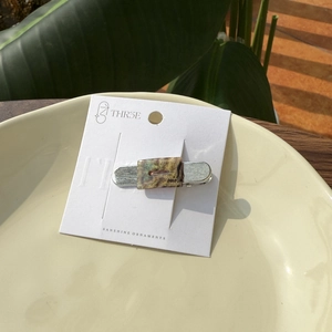 Close-up of a handmade marble pattern acetate hair clip on a white display card
