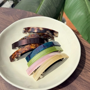 Close-up of colorful marbled acetate hair clips with metal spring fasteners in a tray