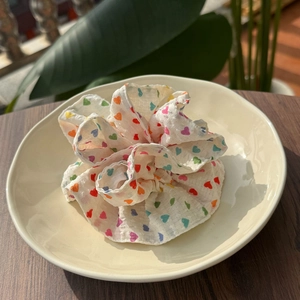 Floral scrunchie with colorful hearts on white seersucker fabric in a ceramic bowl