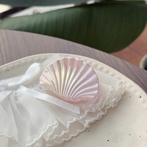 Détail d'une grande pince à cheveux en forme de coquillage rose nacré sur plat