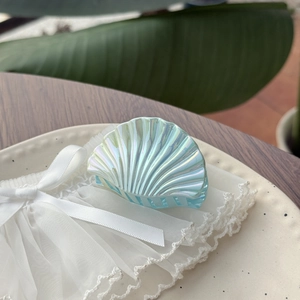 Détail d'une pince à cheveux coquillage avec finition perle holographique sur dentelle