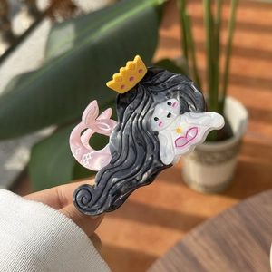 Detailed close-up of a mermaid-shaped acetate hair claw featuring glossy finish and crown