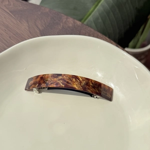 Detailed macro view of an amber textured acetate hair clip with FRANCE Handmade lettering