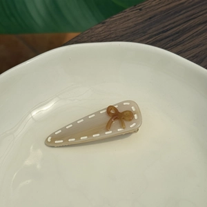 French retro acetate hair clip with marble texture and amber bow decoration on ceramic plate