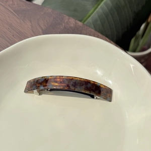Detailed close-up of tortoise shell pattern acetate spring clip with gold text