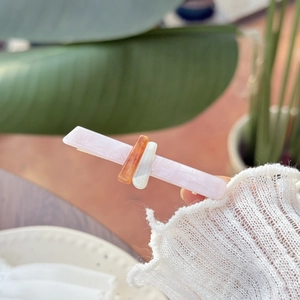 Dettaglio di un fermaglio per capelli in resina rosa marmorizzata con tocchi ambra