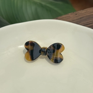 Détail d'une barrette noeud en acétate écaille de tortue avec logo doré fait main