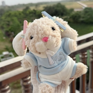 Dettaglio di un coniglio di peluche beige con felpa blu e graziose mollette per capelli